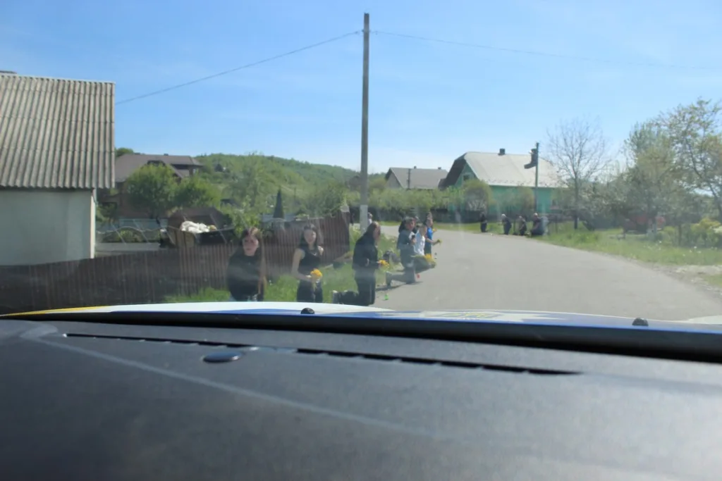 Люди стоять на колінах уздовж сільської дороги
