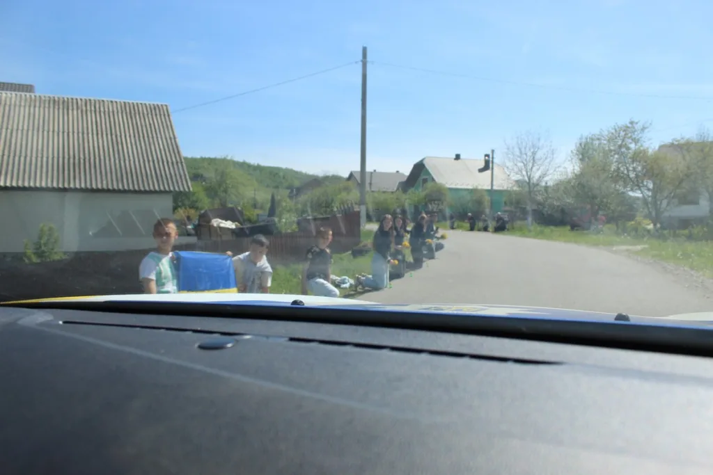 Люди з українським прапором уздовж сільської дороги