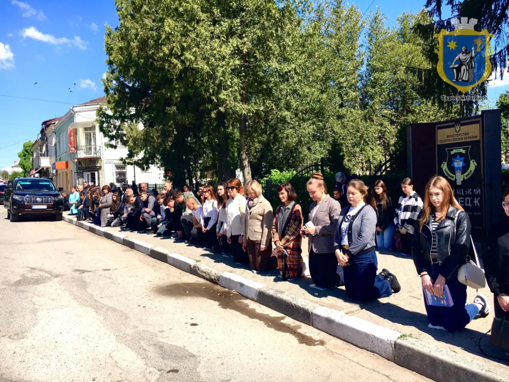 Люди на колінах уздовж вулиці під час церемонії