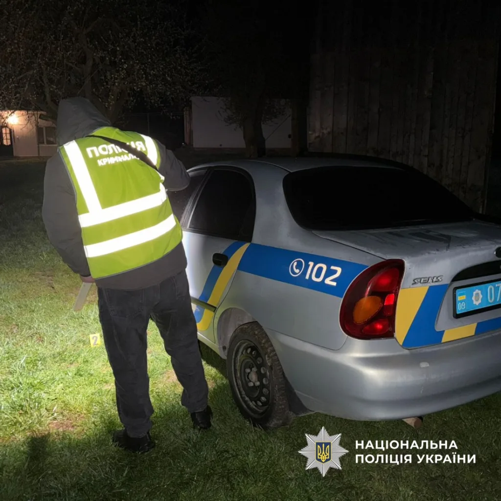 Поліцейський біля службового автомобіля вночі