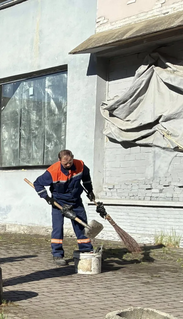 Комунальний працівник прибирає тротуар біля будівлі
