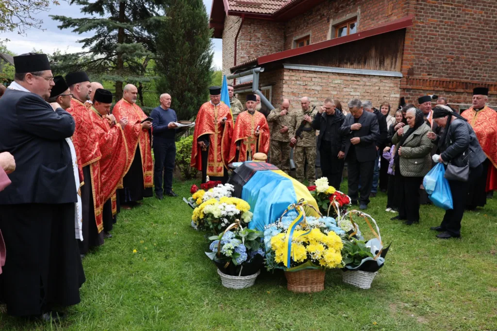Похоронна церемонія з українським прапором і священниками