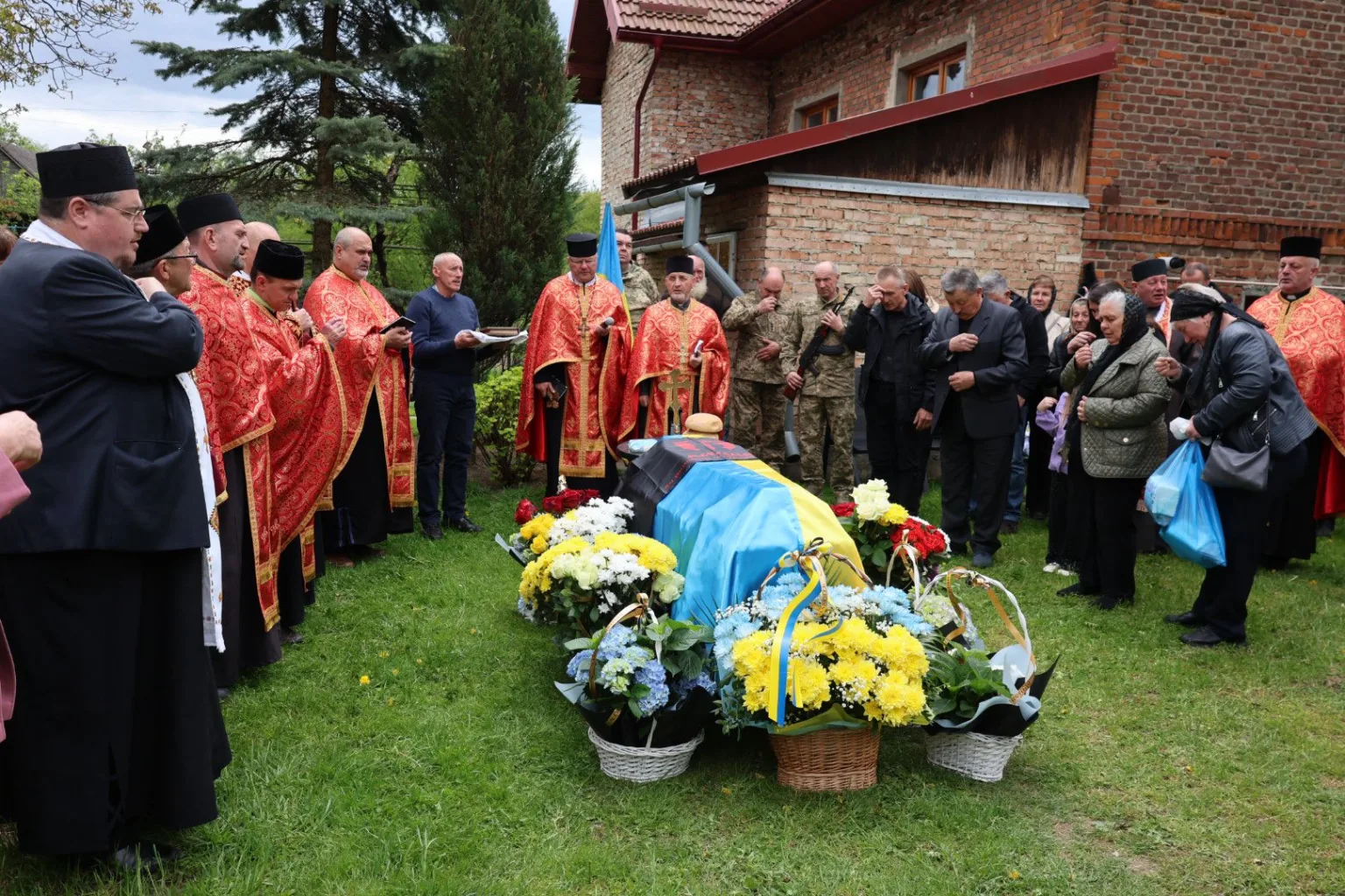 Похоронна церемонія з українським прапором і священниками
