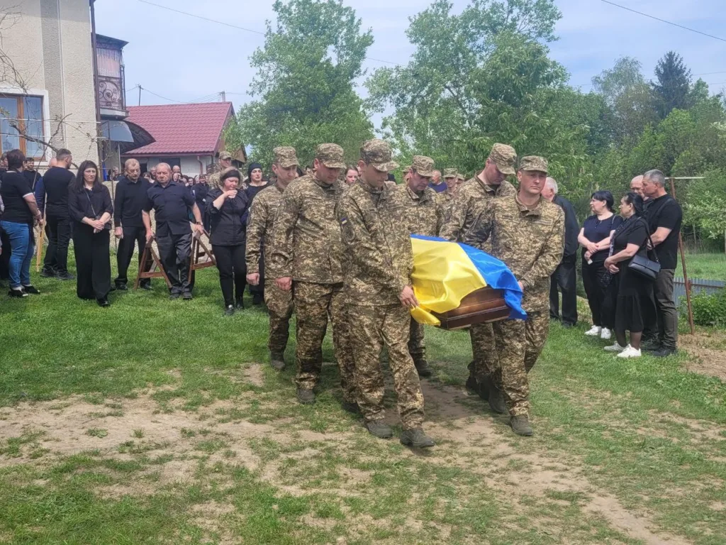 Військові несуть труну, накриту прапором України