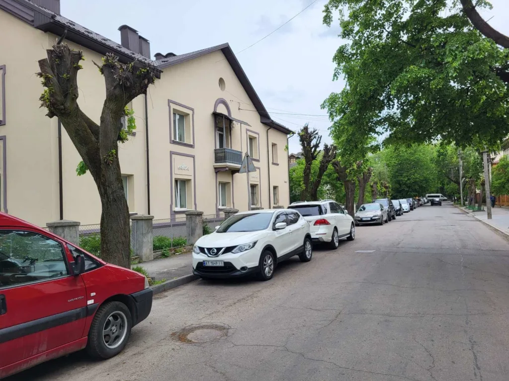 Житлова вулиця з припаркованими автомобілями та деревами