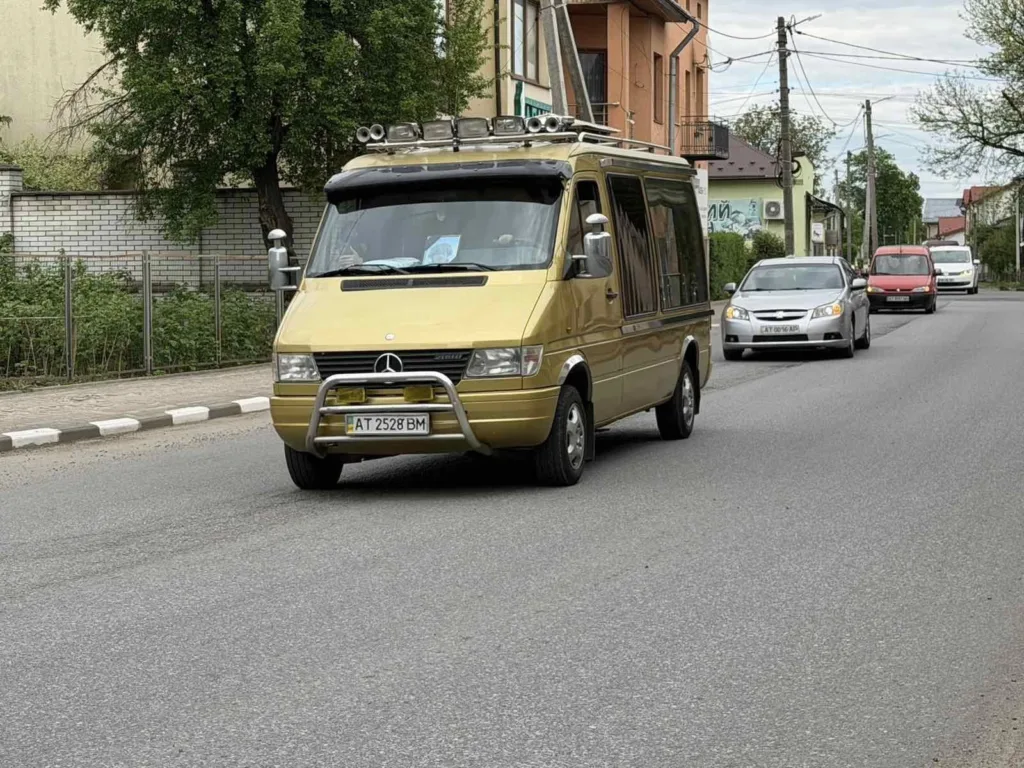 Золотий мікроавтобус Mercedes їде міською вулицею