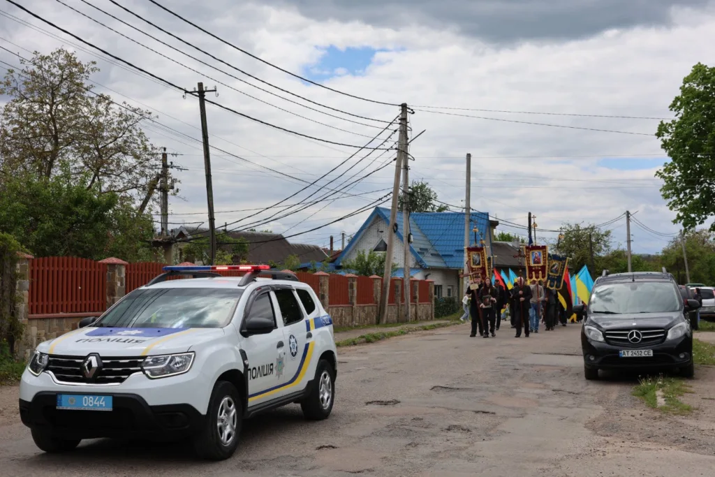 Поліцейське авто супроводжує ходу з українськими прапорами