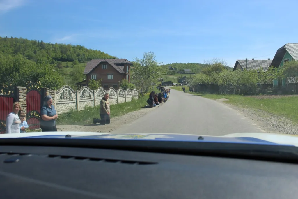Люди стоять колінами вздовж сільської дороги