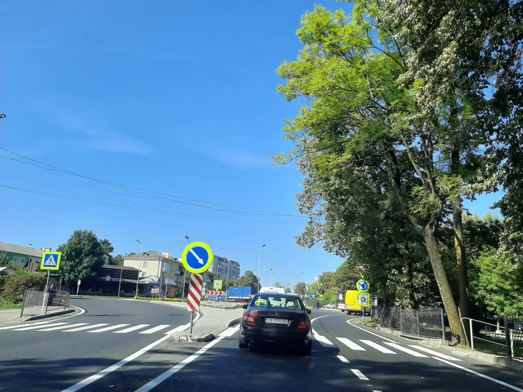 Дорога з розміткою, автомобіль і зелені дерева