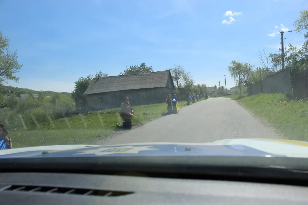 Люди стоять на колінах біля сільської дороги