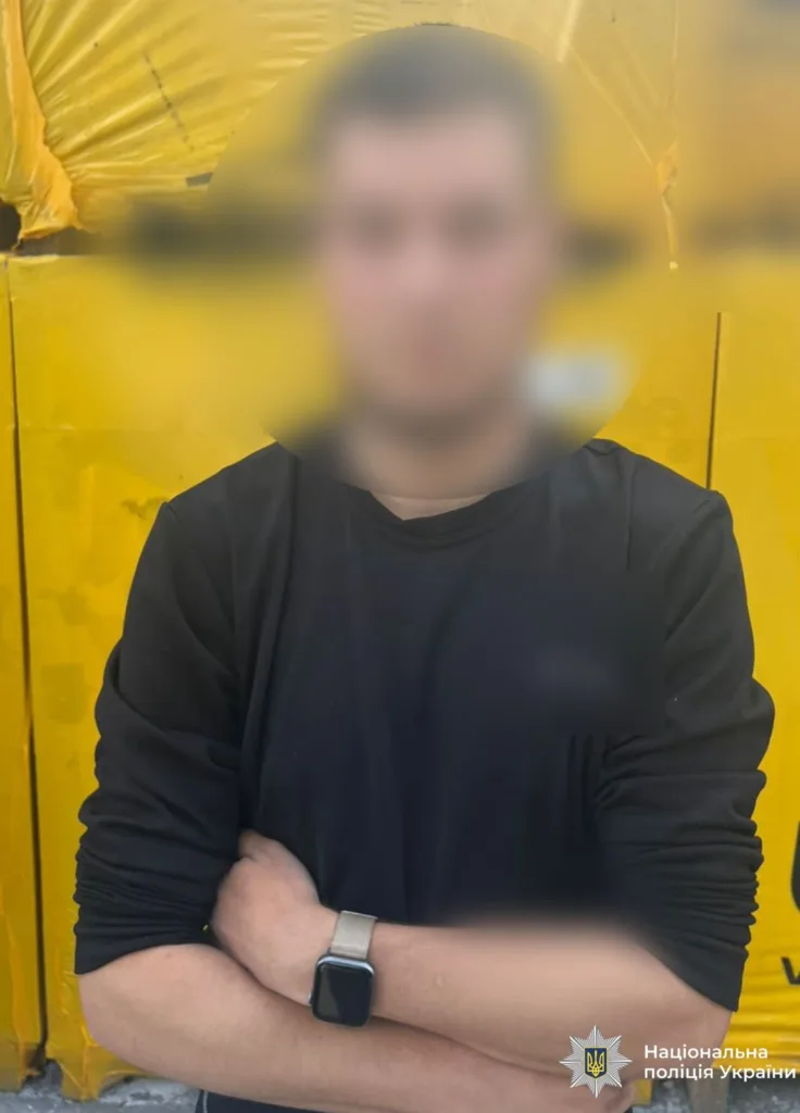 Людина у чорному перед жовтою стіною