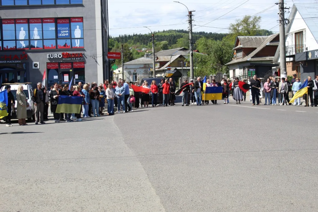 Люди з українськими прапорами стоять на вулиці