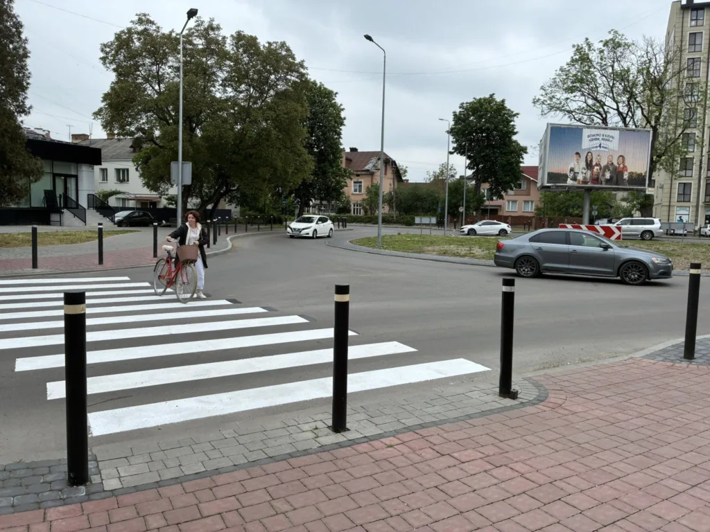 Жінка переходить дорогу з велосипедом на пішохідному переході