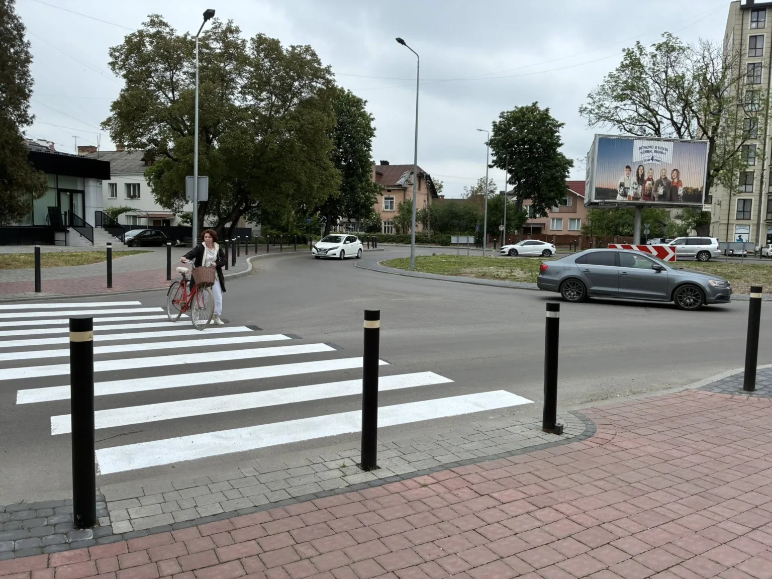 Жінка переходить дорогу з велосипедом на пішохідному переході