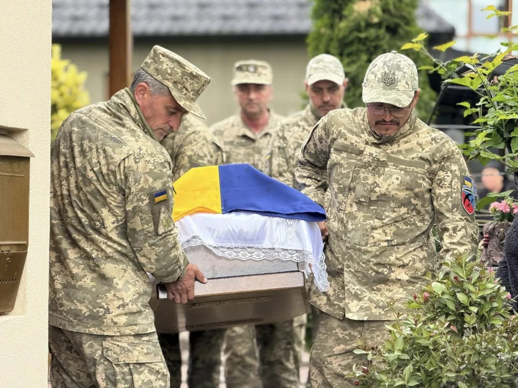 Військові несуть труну, накриту українським прапором