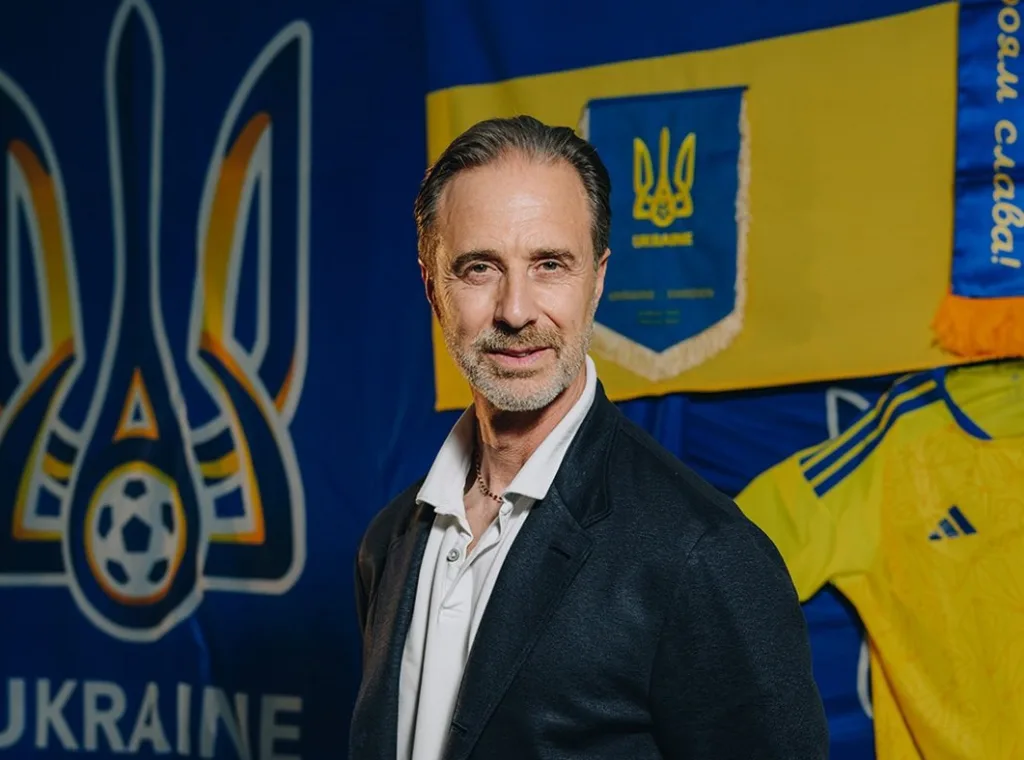 Чоловік перед прапором України та емблемами футболу