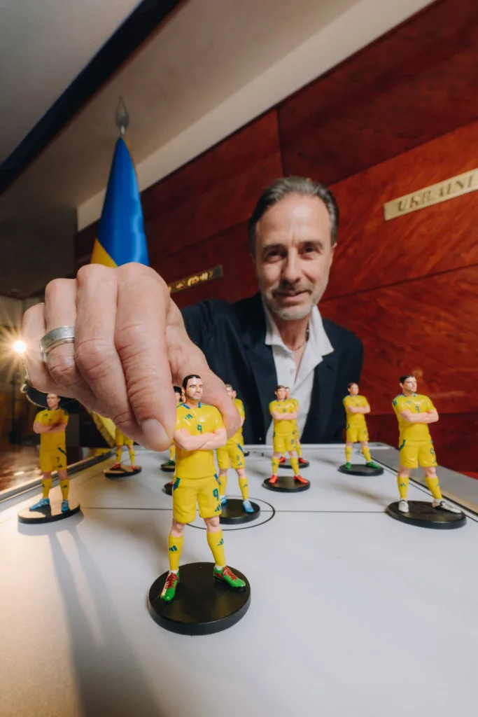 Чоловік показує мініатюрні фігурки футбольної команди України