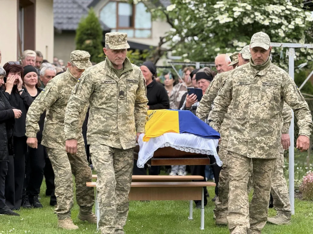 Військові несуть труну, накриту українським прапором