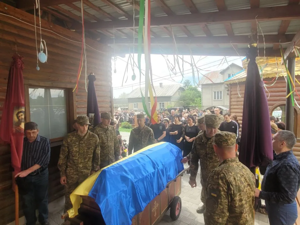Військові несуть труну, покриту прапором України