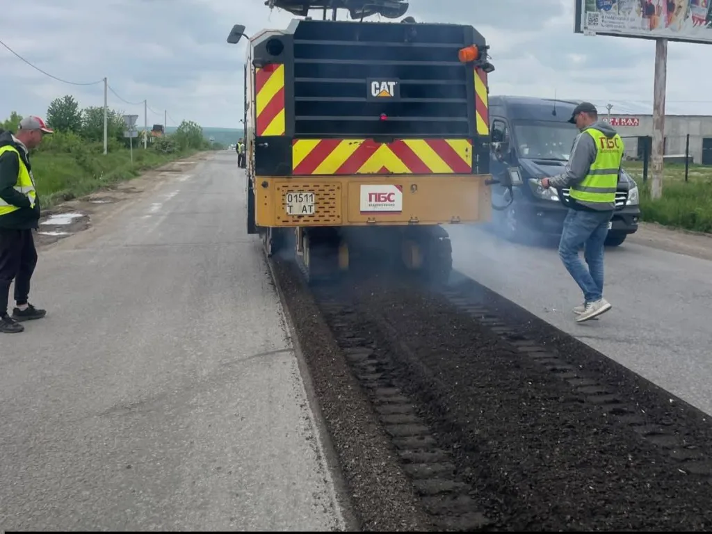 Працівники ремонтують асфальтну дорогу дорожньою технікою