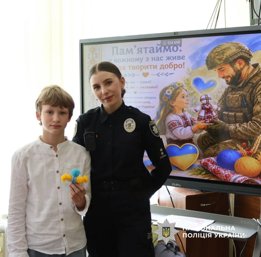 Поліцейська та хлопчик поруч із патріотичним плакатом