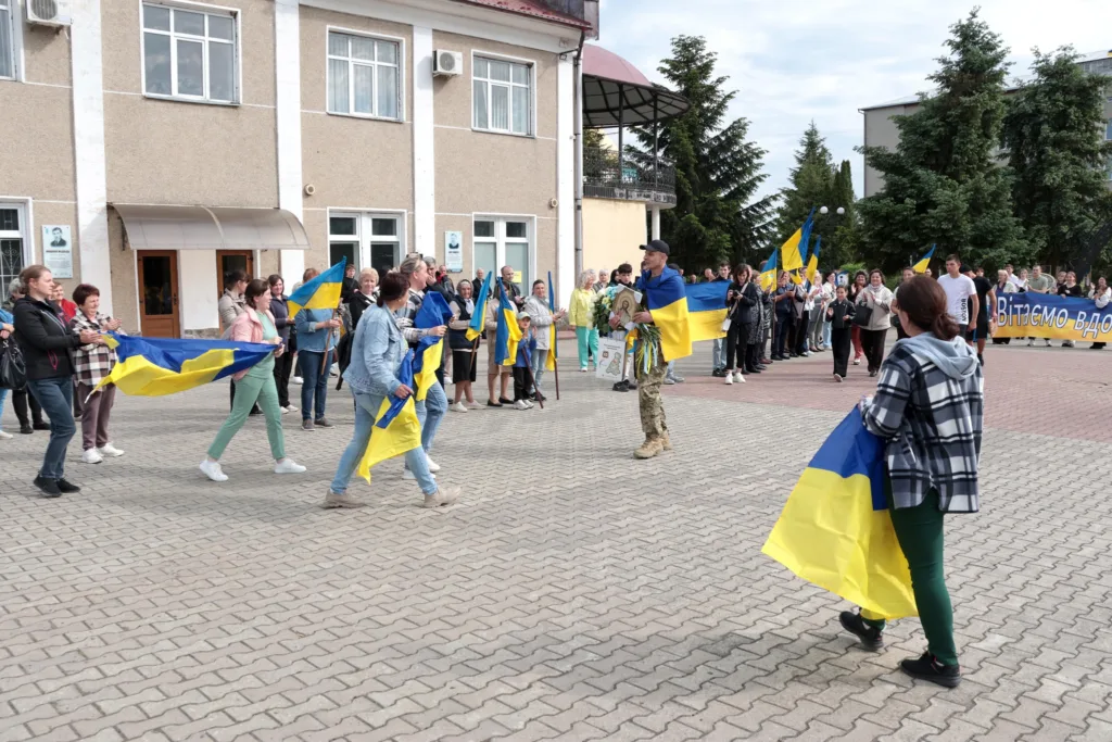 Зустріч військового з українськими прапорами на площі
