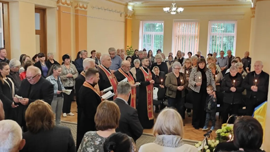 Люди стоять у залі на поминальній церемонії