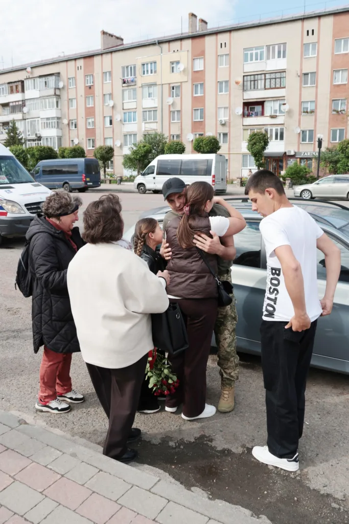 Родина обіймає військового на вулиці міста