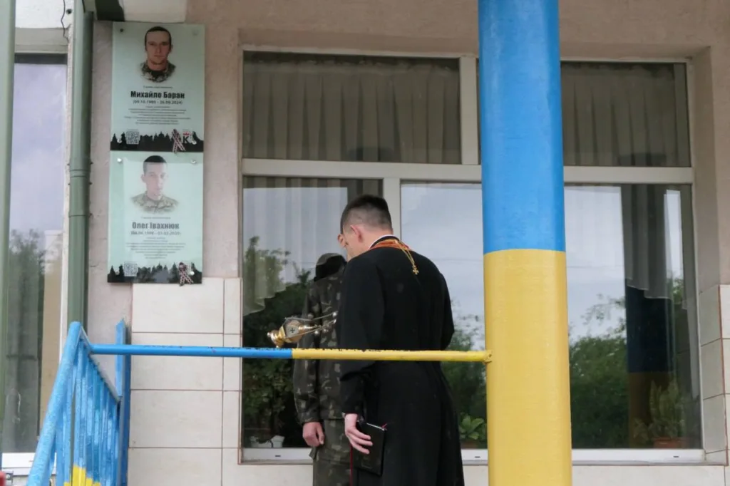 Священник молиться біля меморіальної дошки воїнам