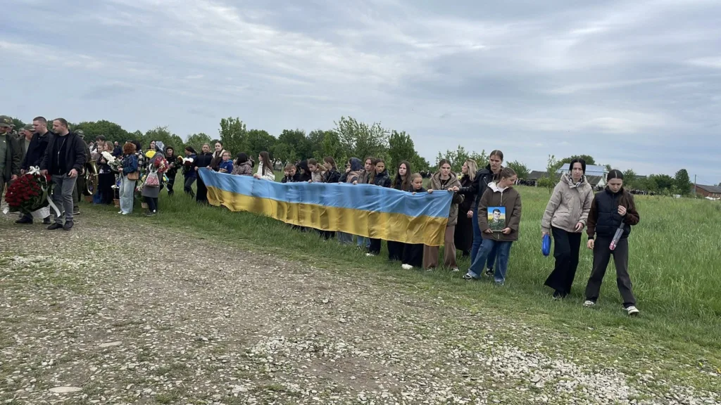 Люди з українським прапором на церемонії прощання