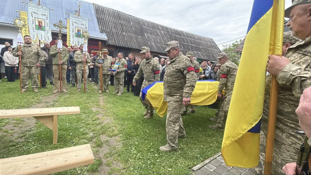 Військові несуть труну, накриту українським прапором