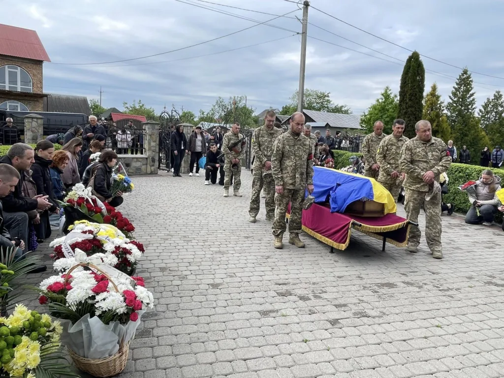 Військові несуть труну, накриту прапором України