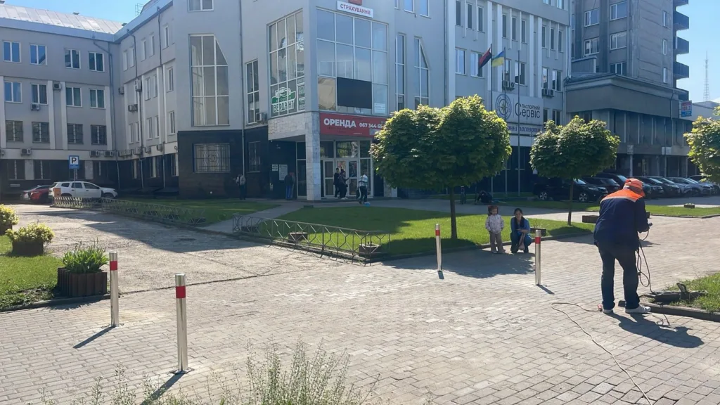 Офісна будівля з парковкою та людьми біля входу