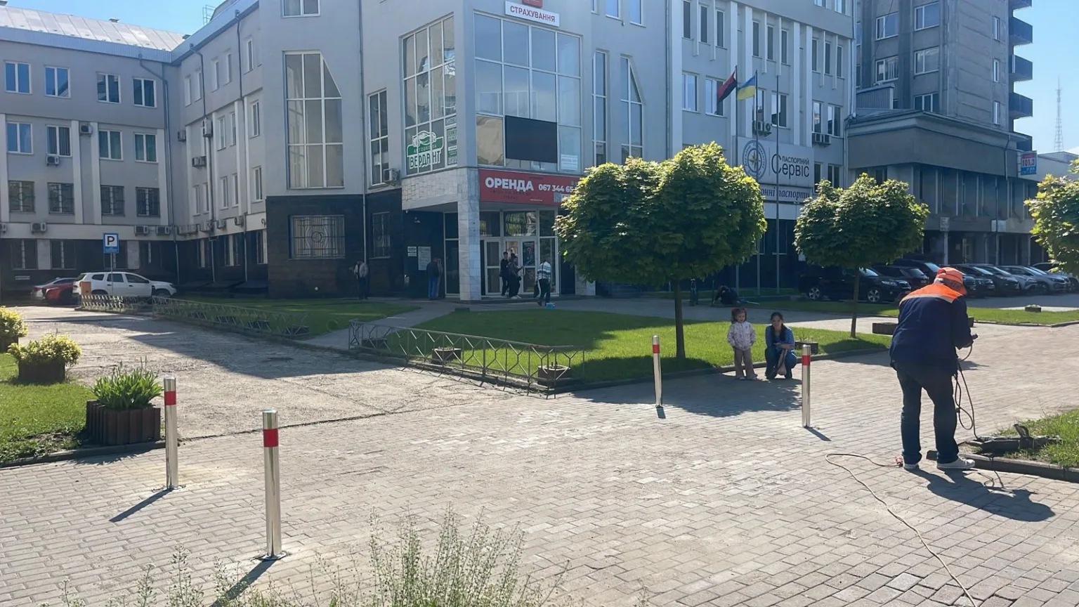 Офісна будівля з парковкою та людьми біля входу