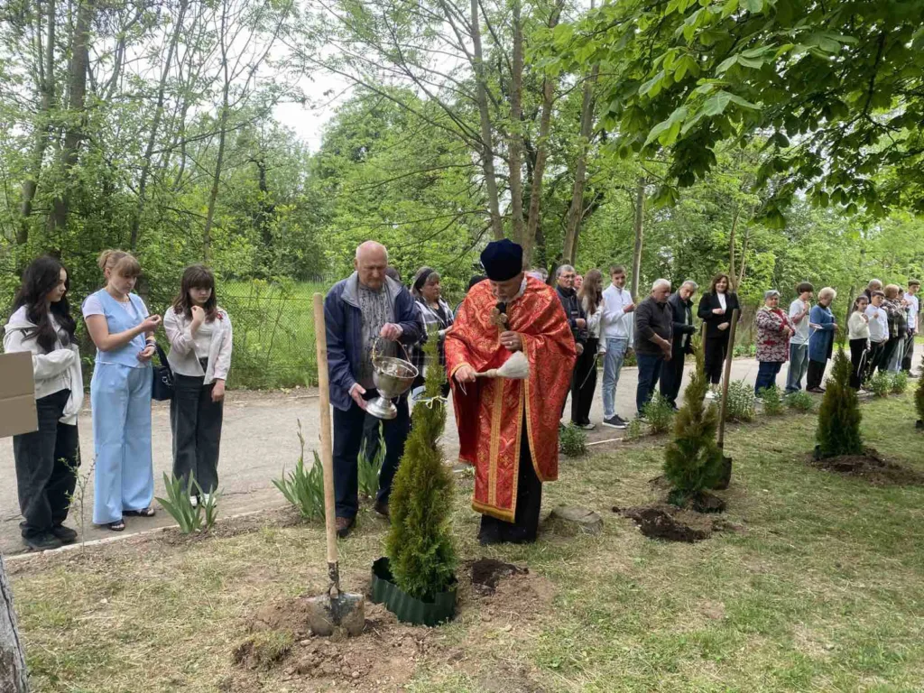 Священник освячує саджанці дерев під час церемонії.