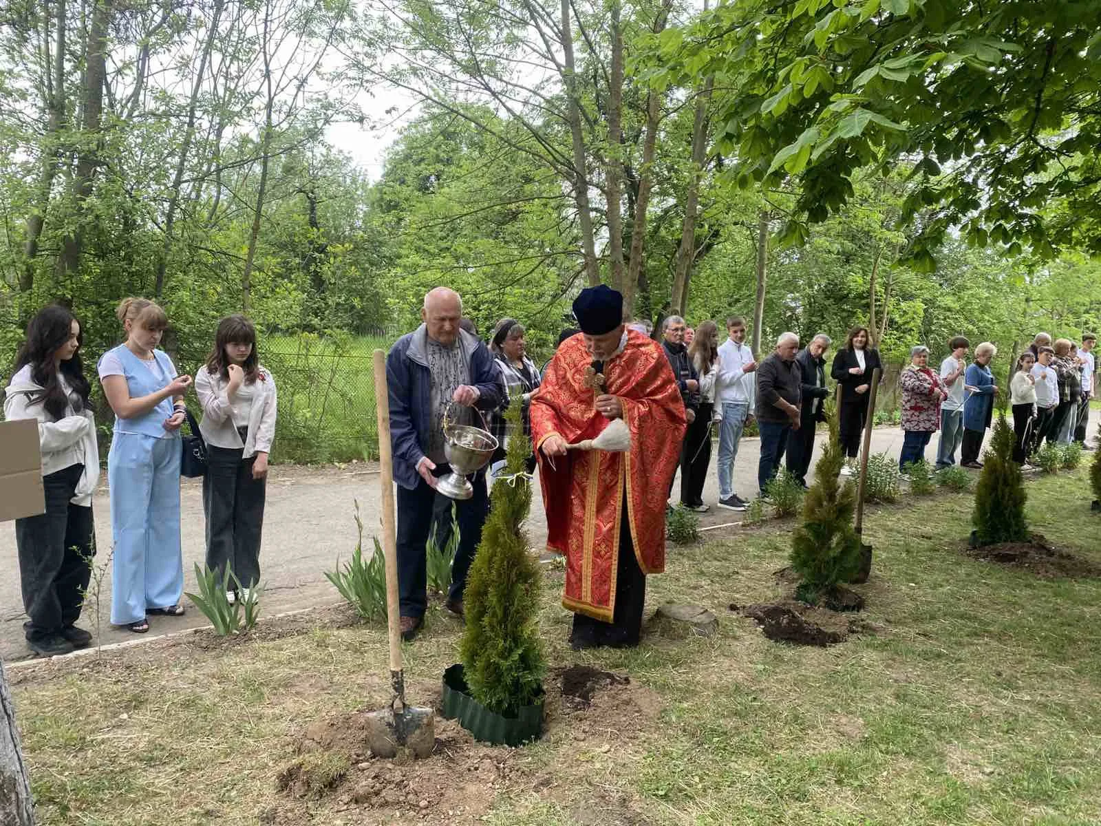 Священник освячує саджанці дерев під час церемонії.
