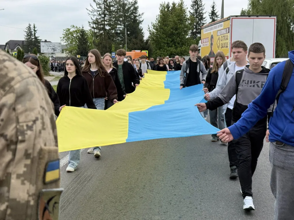 Люди несуть великий прапор України на вулиці