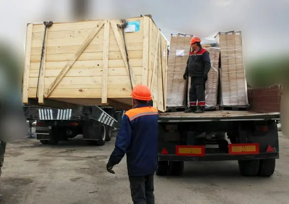 Робітники вантажать великі дерев’яні ящики на вантажівку