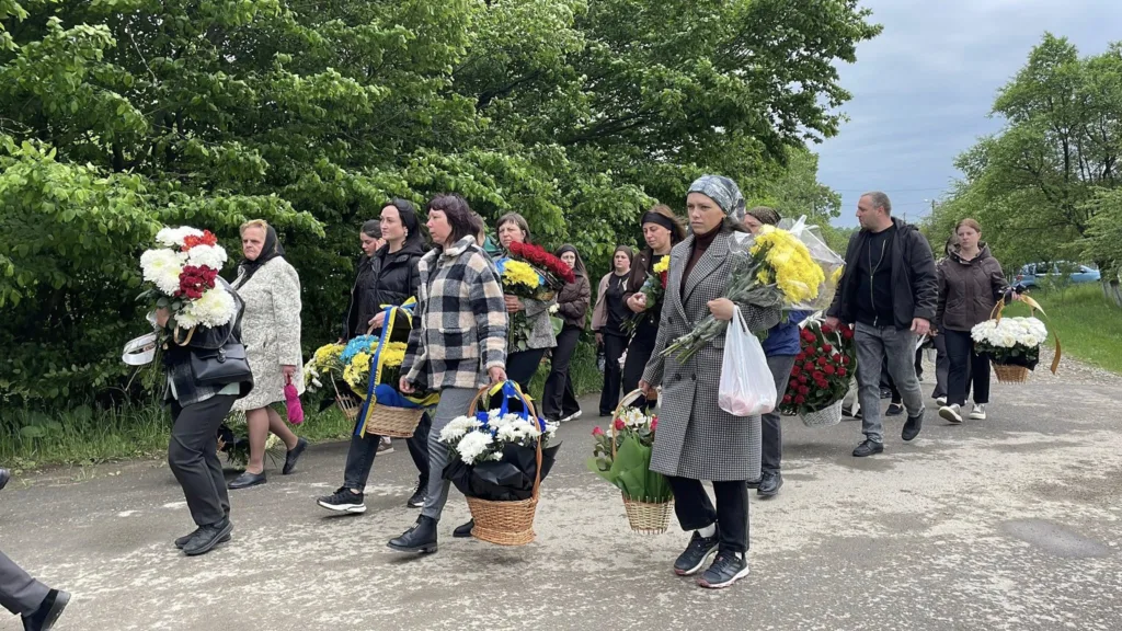 Люди несуть квіти під час похоронної процесії
