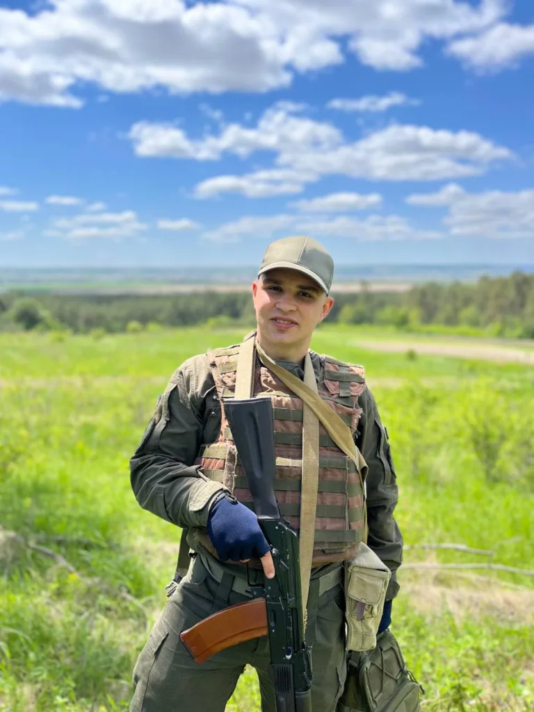 Військовий стоїть у полі з автоматом