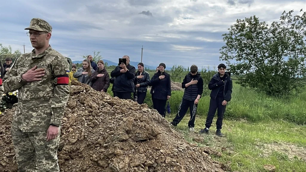 Військовий і люди на похороні українського солдата