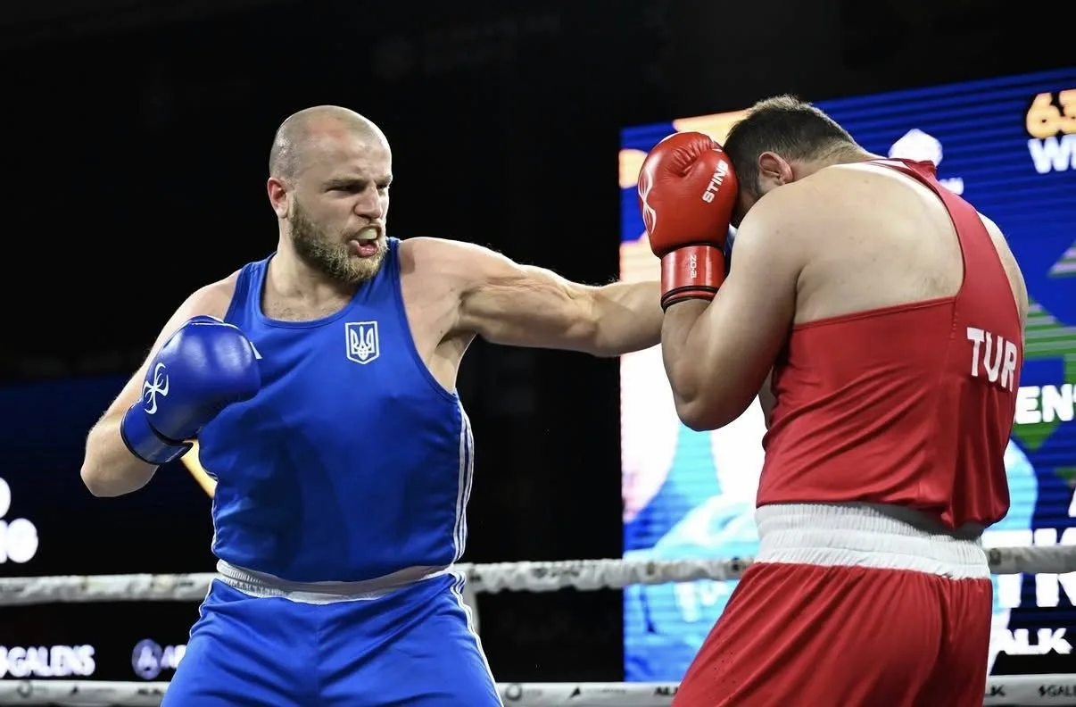 Боксер у синій формі атакує суперника в червоній