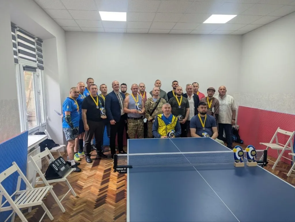 Група чоловіків з медалями біля тенісного стола