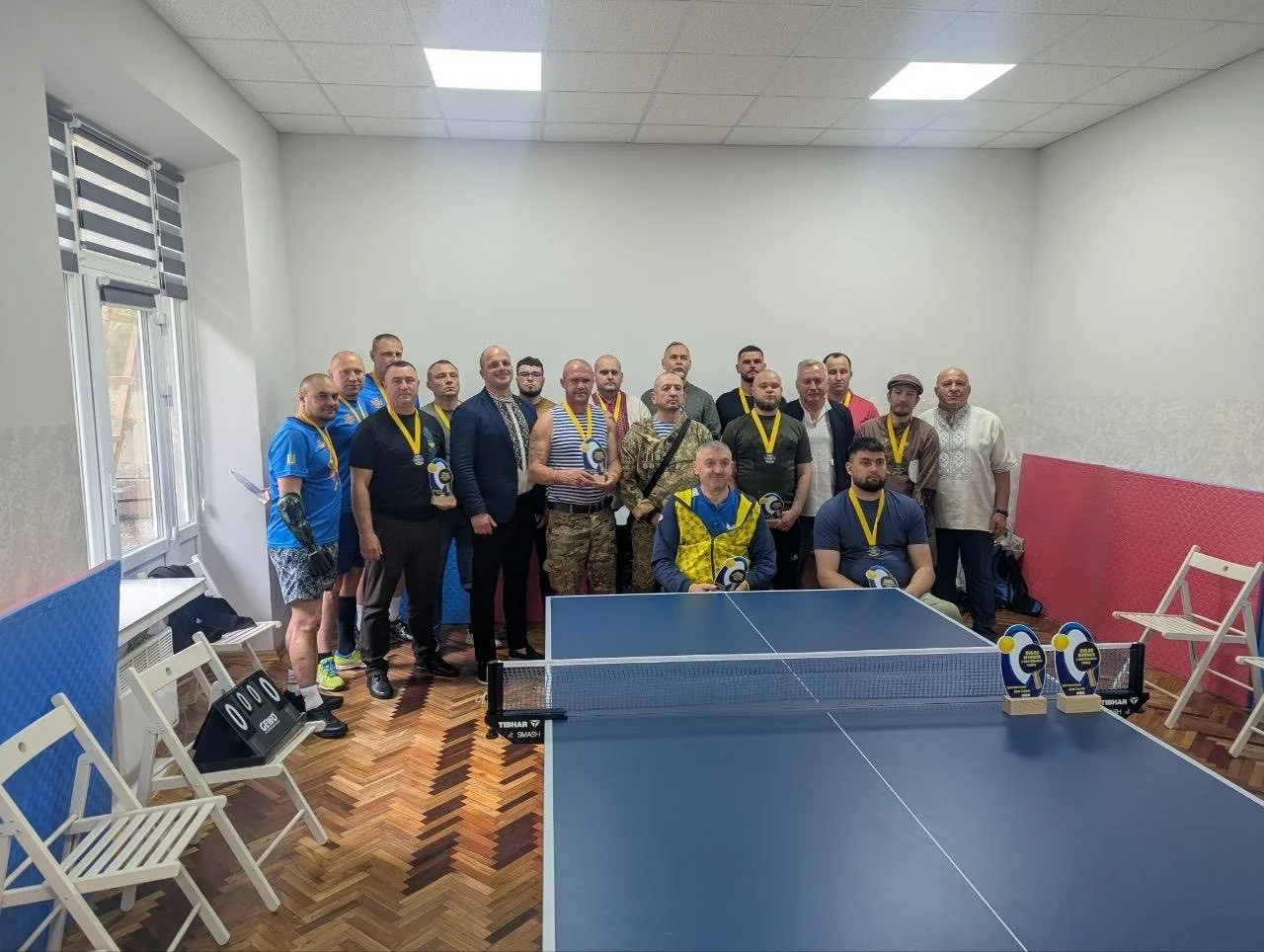 Група чоловіків з медалями біля тенісного стола