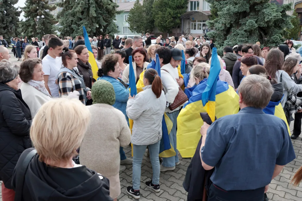 Натовп людей з українськими прапорами на вулиці