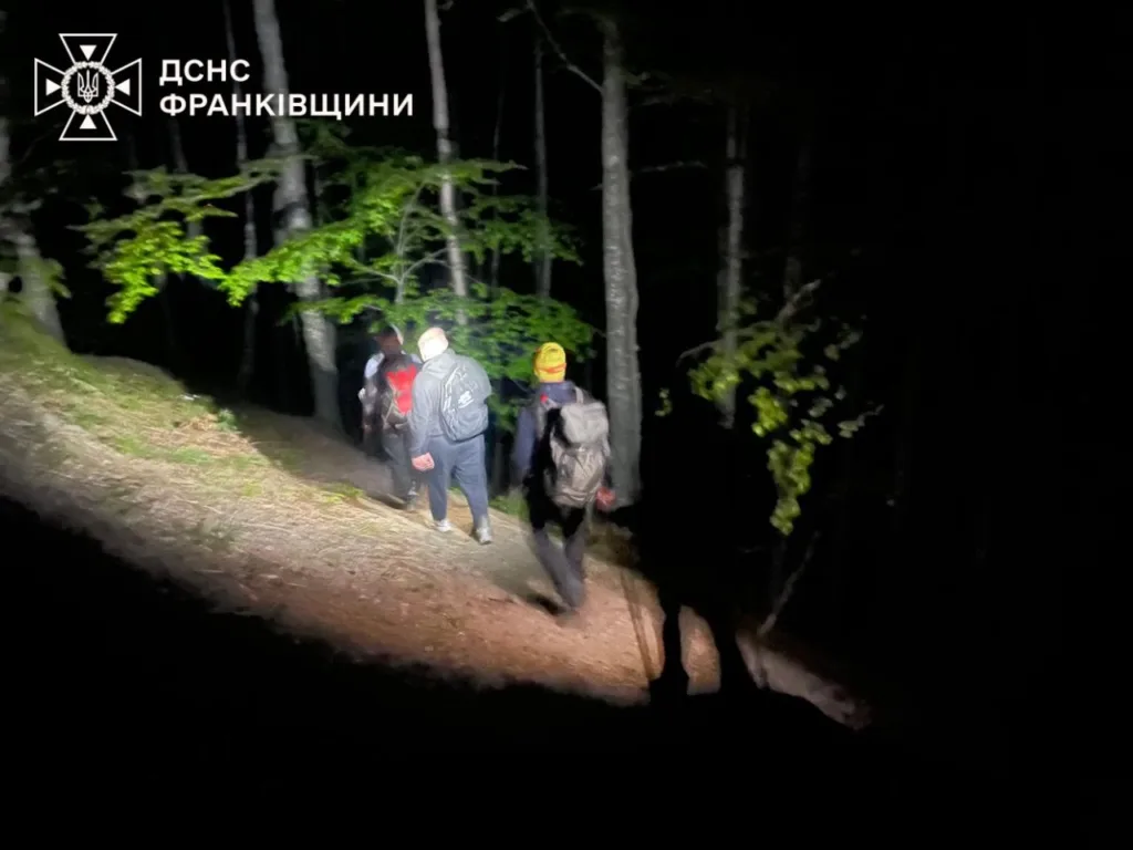 Рятувальники йдуть лісом уночі з ліхтарями