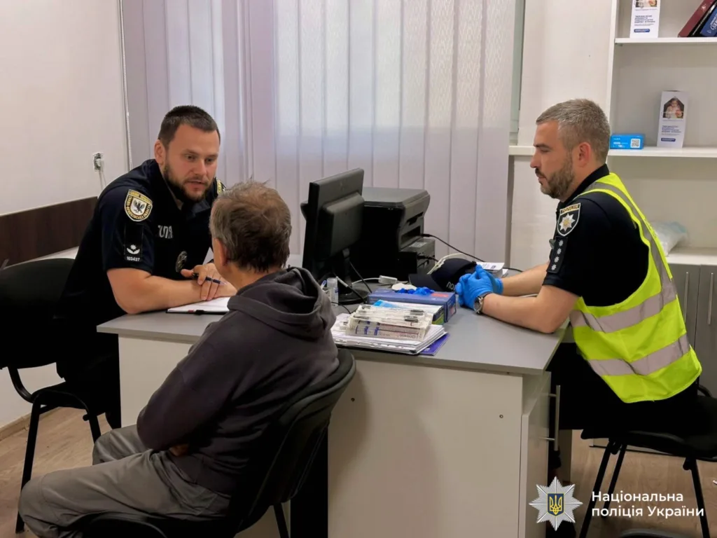 Поліцейські спілкуються з чоловіком у відділку поліції