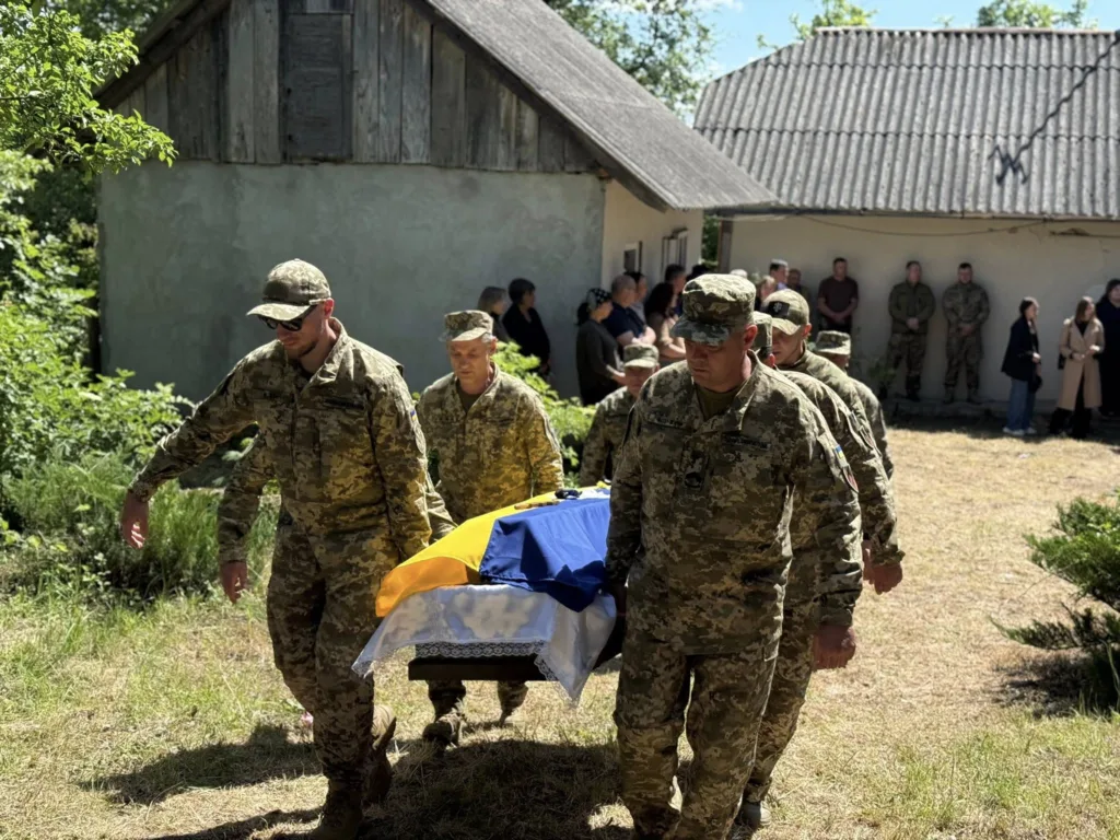 Військові несуть труну, накриту українським прапором