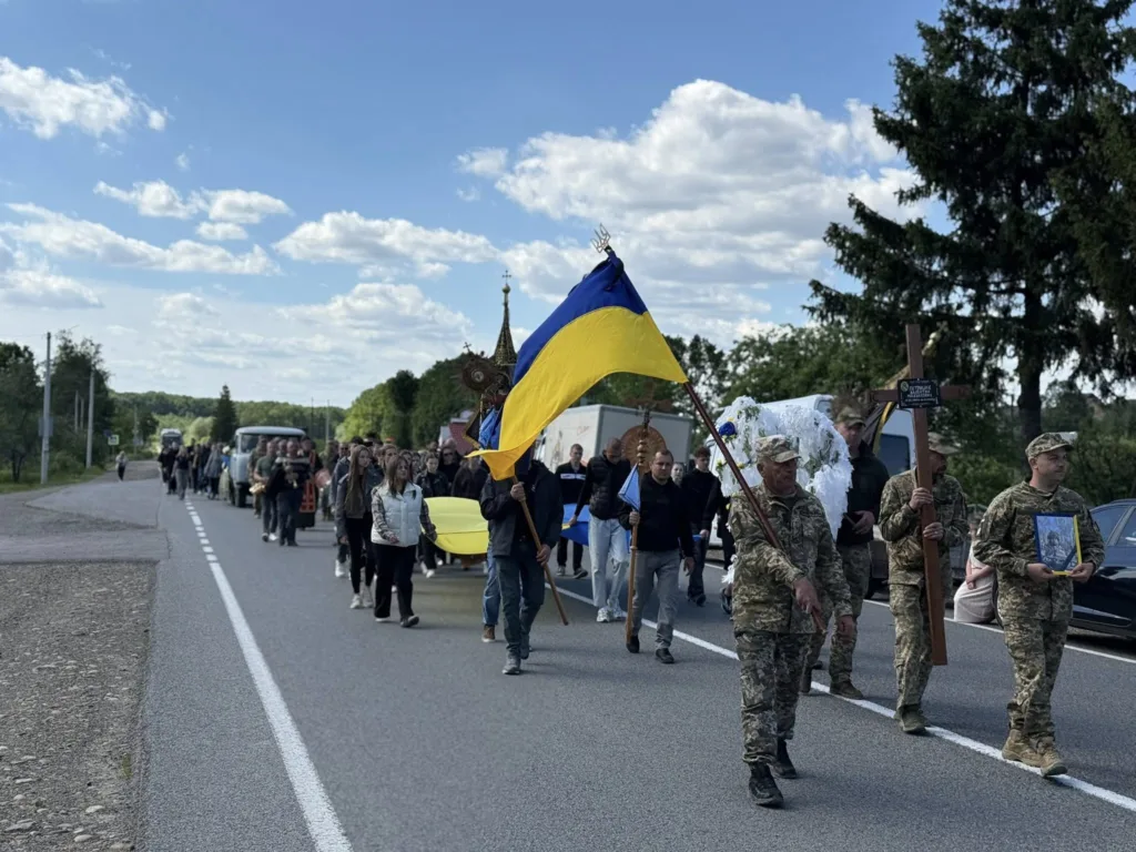 Процесія з українським прапором на сільській дорозі