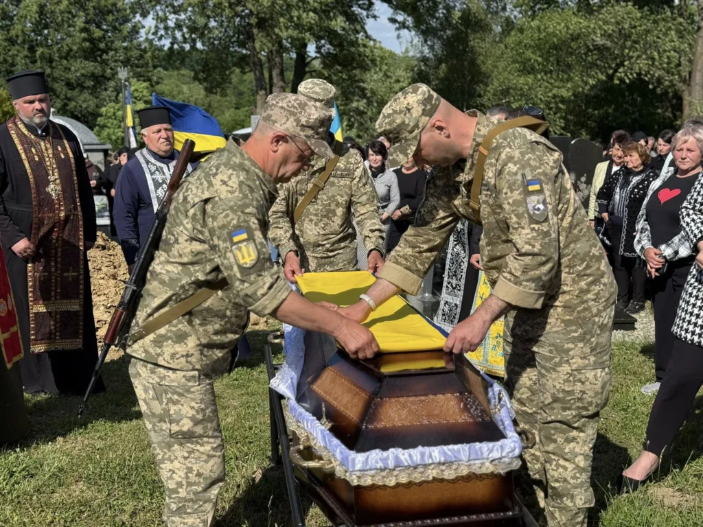 Військові накривають труну українським прапором